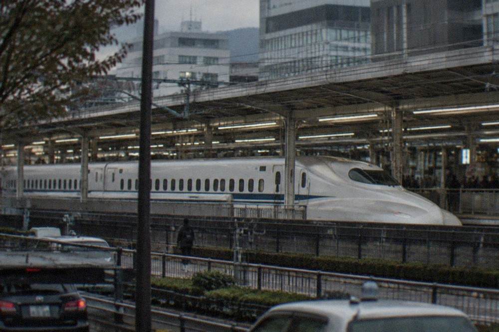 A long white shinkansen train waiting on a platform at a large city station