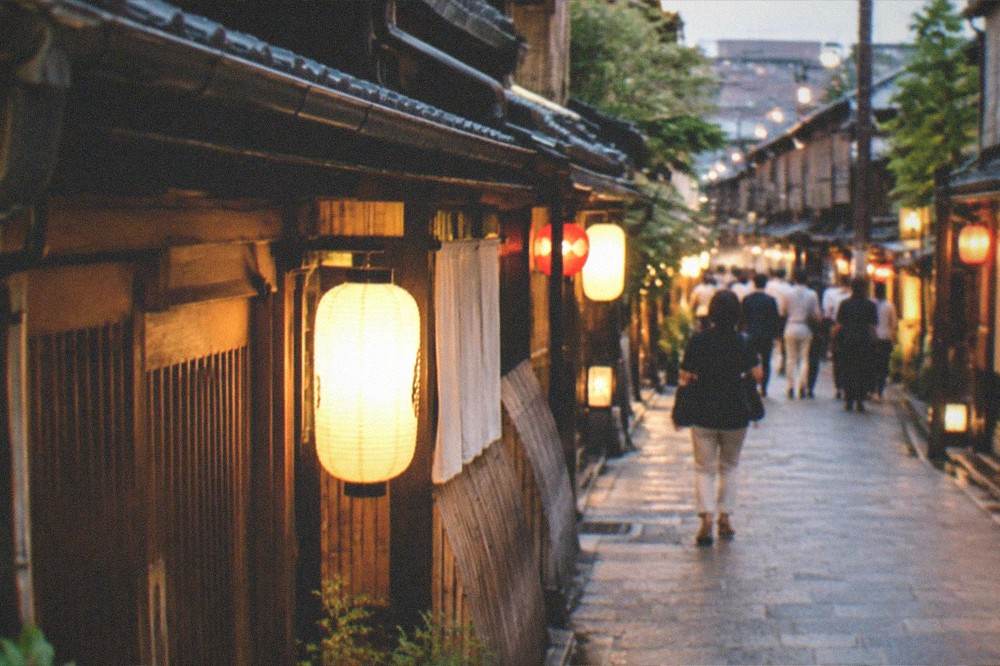 Lanterns glowing along a traditional street in Gion at night with wooden facades