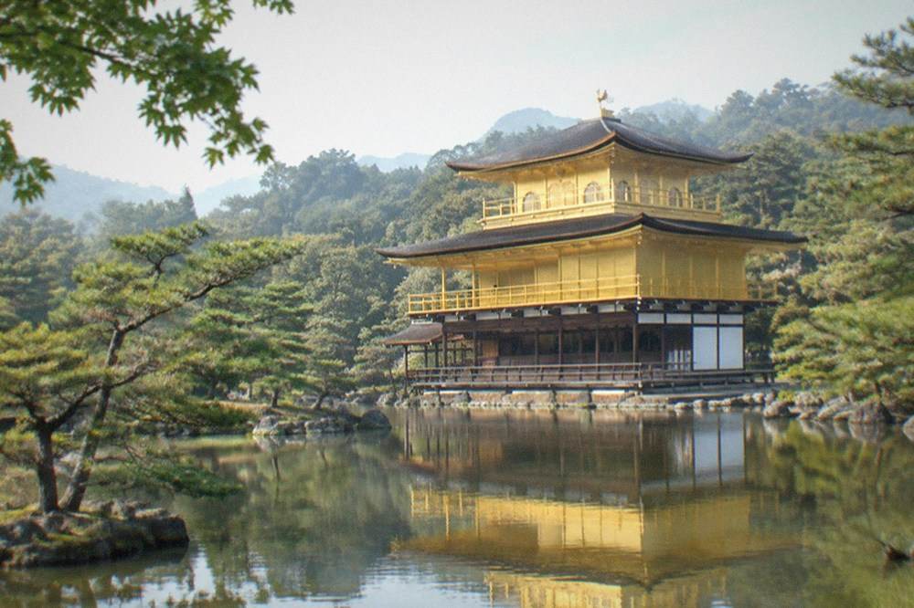The golden pavilion of Kinkaku-ji reflected in its pond surrounded by trees