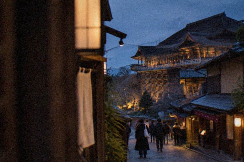 A wooden temple platform lit by warm floodlights against a dark sky