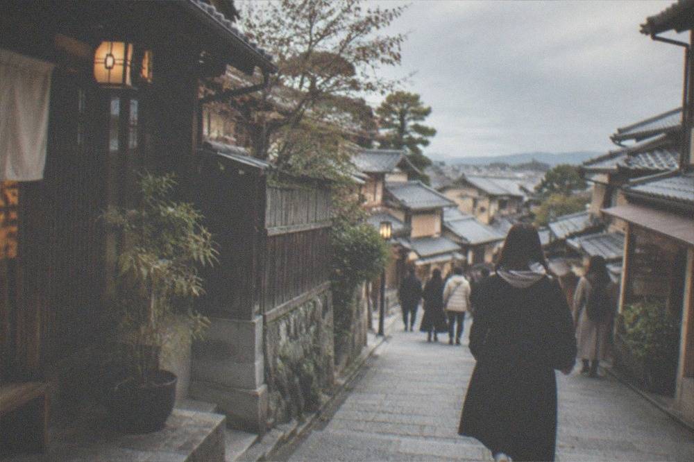 Visitors walking the preserved stone slope of Sannenzaka lined with wooden machiya shopfronts