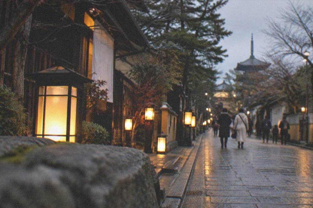 Lanterns glowing along a snowy lane in Kyoto on a December evening