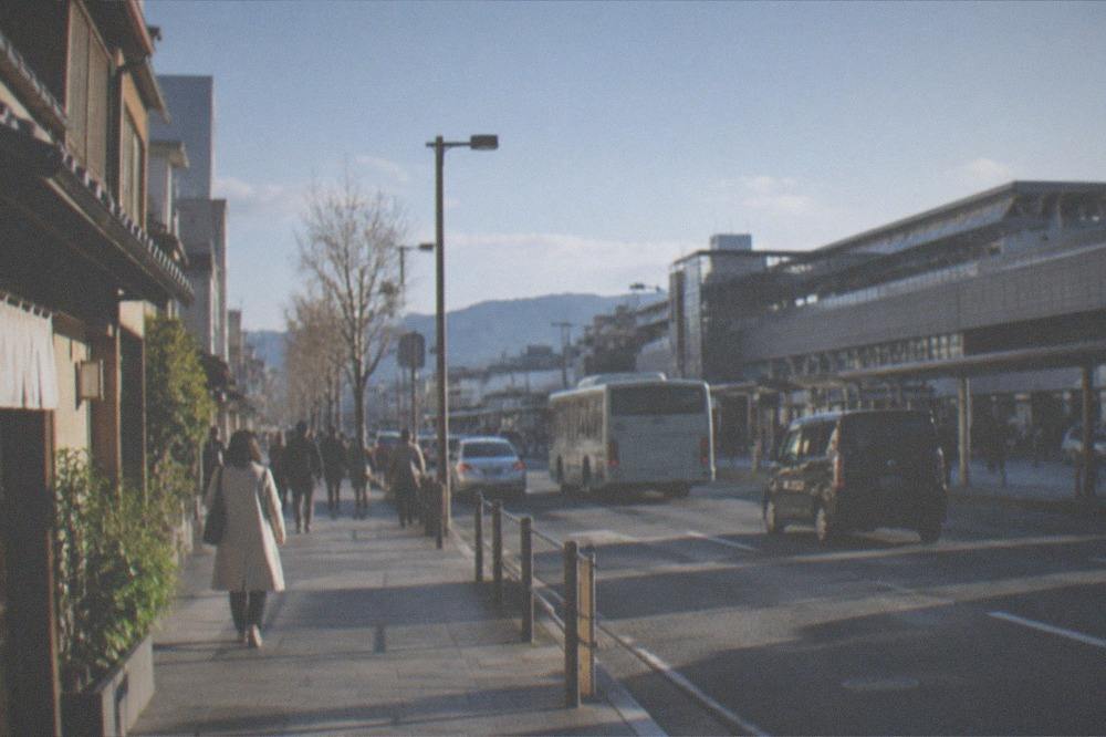 Kyoto city bus stopped at a street corner with passengers boarding