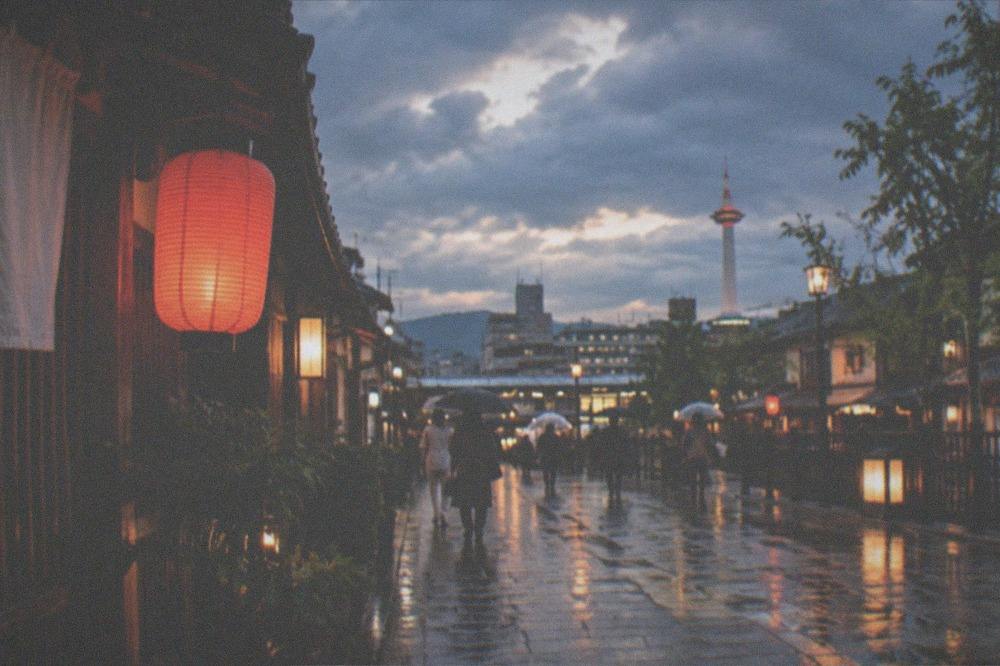 Wet lanterns reflecting on a stone street in Kyoto at night after rain