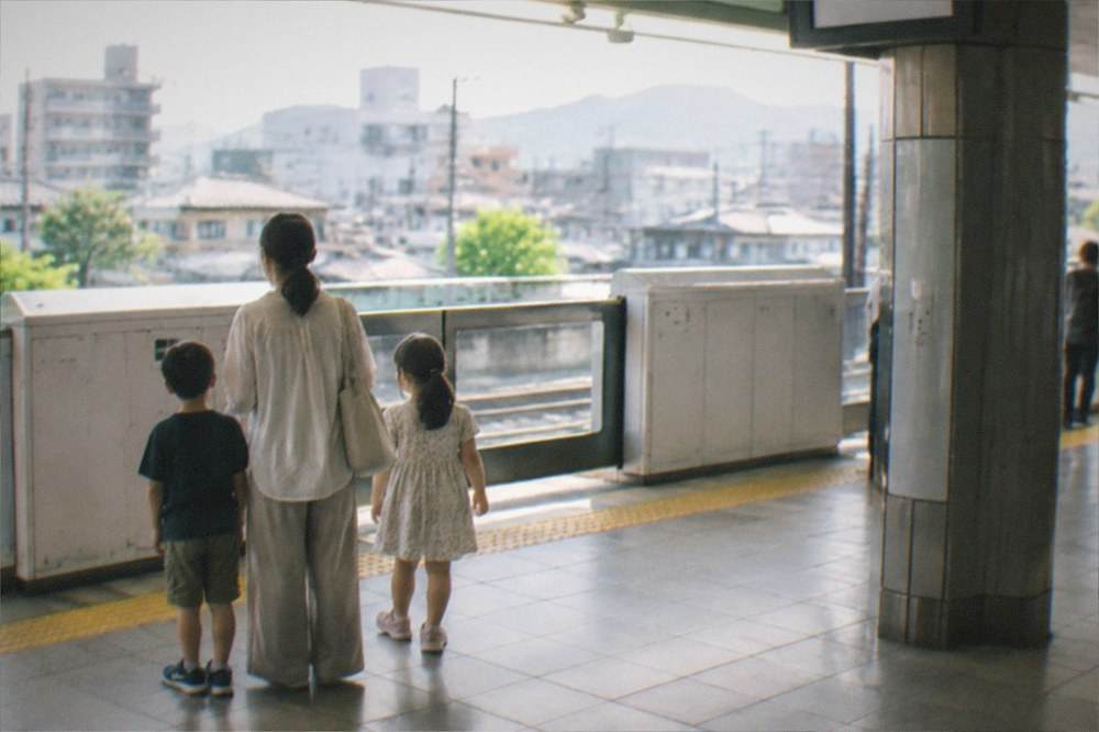 A parent and two children waiting on a clean Kyoto subway platform