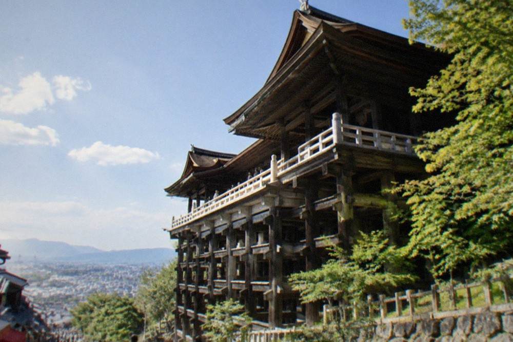The wooden stage of Kiyomizu-dera seen from below, with the city of Kyoto spreading out behind it
