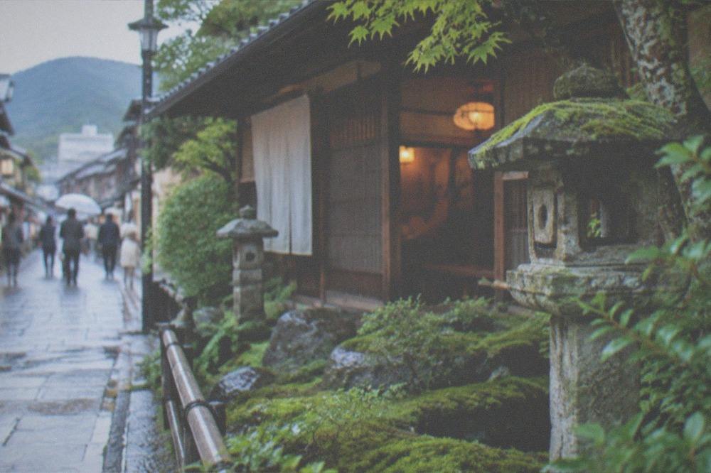 A traditional wooden teahouse beside a moss garden in Kyoto with stone lanterns